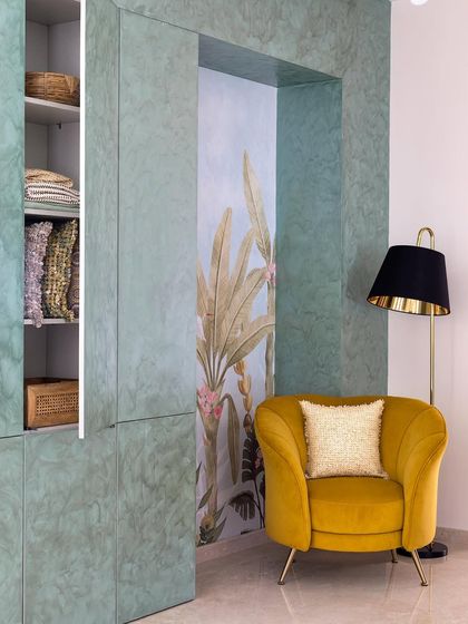 Upon entering this home, your eyes are drawn to this beautiful concealed storage unit. A niche with a Kalakaarihaath wallpaper and a vibrant yellow armchair creates a stunning focal point in the extended foyer.