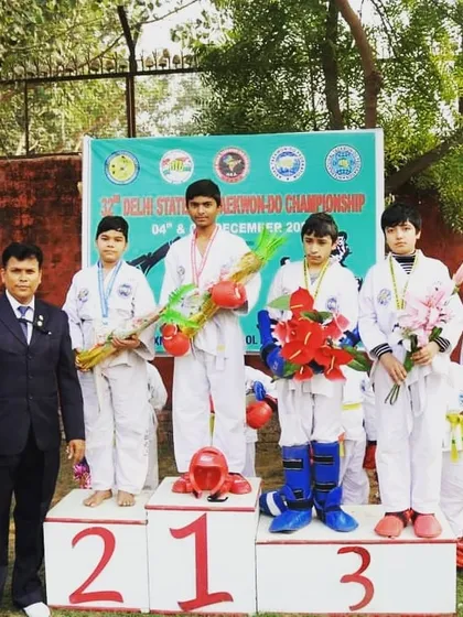 A group of my male students on the victory podium at a state-level competition. Their success in sparring events is a direct result of our rigorous training regimen.