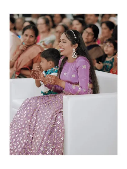 The bride enjoying her reception, her happy expression captured as she sits with a young guest.