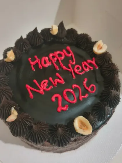 For the chocolate lovers, here is a rich chocolate New Year's cake. It's topped with chocolate frosting, hazelnuts, and a festive "Happy New Year 2026" message.