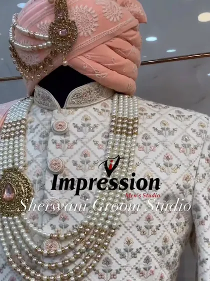 The classic white and peach combination is timeless. This intricately embroidered white sherwani, paired with a delicate peach pagdi and a multi-layered pearl mala, is designed to perfectly complement the bride's attire.