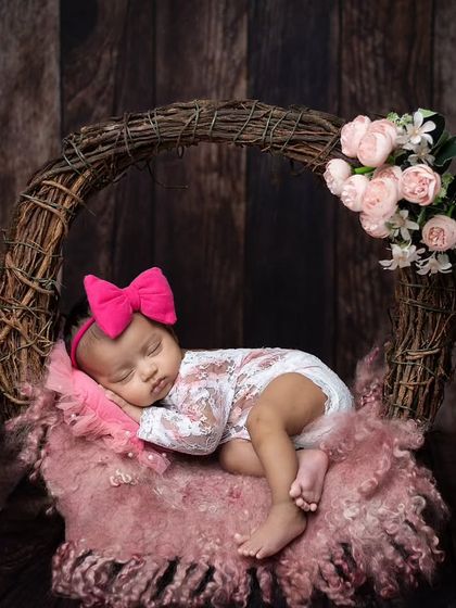 A wider shot of the pink wreath setup, showing the baby comfortably asleep on a plush pink rug.