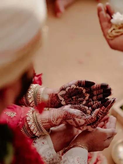 A candid moment during a wedding ceremony, highlighting the dark and intricate henna stain on the bride's palms. My natural henna ensures a color that stands out in every ritual.