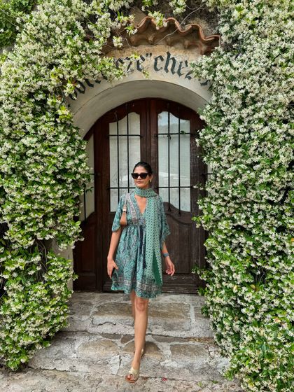 A full-length shot of my outfit in Eze, France. The combination of the printed dress, matching scarf, and metallic sandals makes for a perfectly coordinated and photogenic travel look.