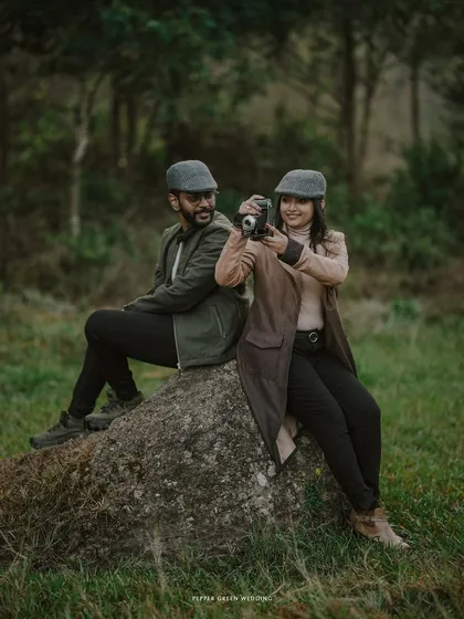 A playful moment during a vintage-themed pre-wedding shoot, where the couple uses an old camera as a prop to enhance their story.