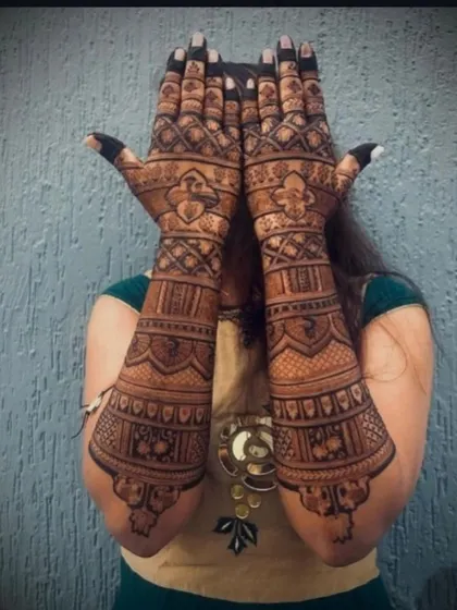A full-arm design with geometric patterns, checks, and floral bands, showcasing a different style of traditional mehandi.