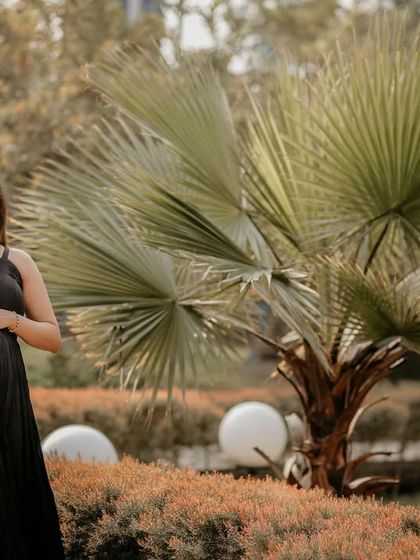 A solo maternity portrait taken in a beautifully landscaped garden. The composition uses the natural elements, like the fan palm, to create a unique and stylish frame.