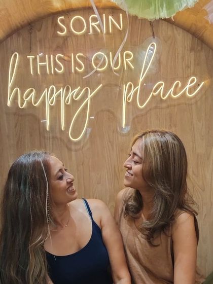 The "happy place" sign is the perfect backdrop for capturing the joy of a shared salon experience between friends.
