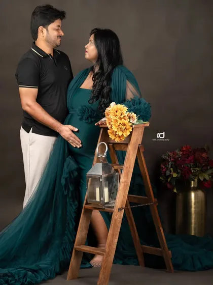 Sharing a look of love and excitement. The lantern and floral props add a rustic, warm touch to this couple's portrait in a gorgeous dark green gown.