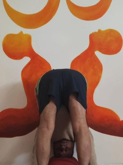 A standing forward bend, Uttanasana, with the head resting on a support to encourage release.