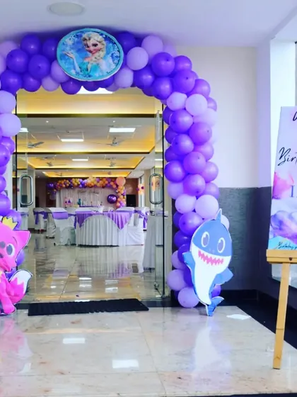 The entrance to Inara's party, featuring a purple and lavender balloon arch with Baby Shark and Frozen character cutouts, hinting at a fun, multi-themed celebration.