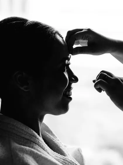 A silhouette of the bride, Amrutha, getting her makeup done. This black and white shot focuses on the form and the action, creating an artistic and timeless image of the getting ready process.