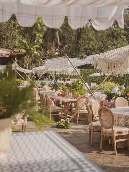A wide view of the brunch setup, showing the mix of dining tables and lounge areas under macrame-fringed umbrellas.