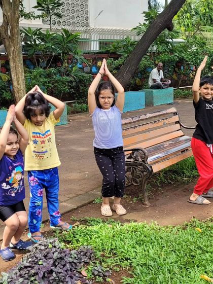 Our outdoor yoga sessions are a chance to connect with nature. Here, the children are practicing Vrikshasana, or tree pose, finding their balance among the real trees in the park.