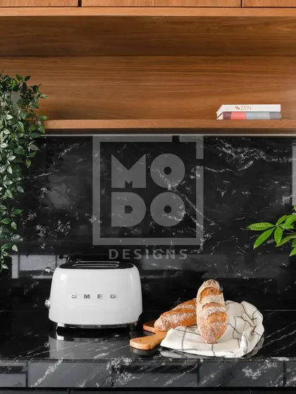 Welcome to the heart of the home. This modular kitchen features a beautiful black marble countertop and backsplash, complemented by natural wood shelving and a touch of greenery.