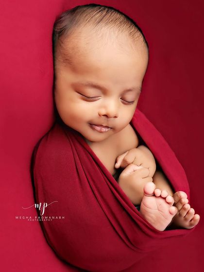 A sweet, sleepy smile from a baby wrapped in red. These are the moments that melt our hearts.