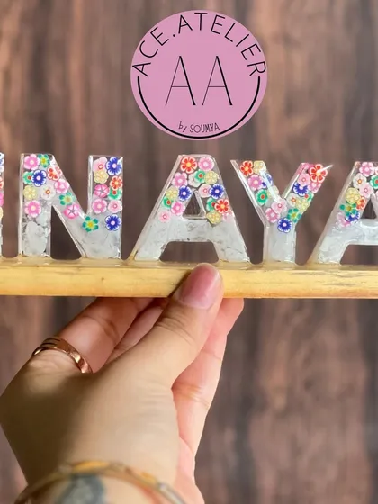 A closer look at the 'Inaya' name stand, showing the detail of the tiny flowers embedded within the letters. Each one is placed by hand to create a unique design.
