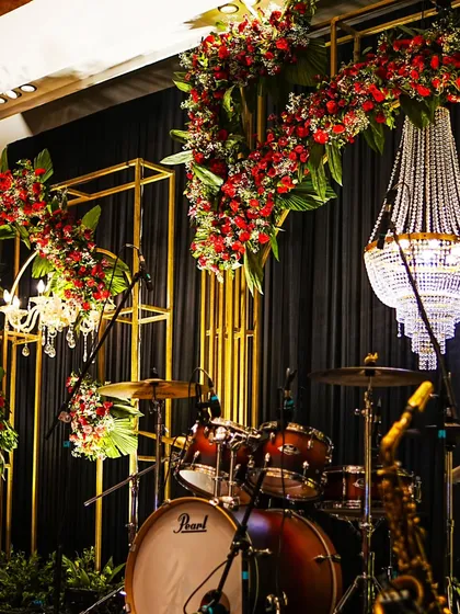 Another perspective of the performance stage, highlighting the interplay between the warm gold structures, vibrant red florals, and the classic black draping.