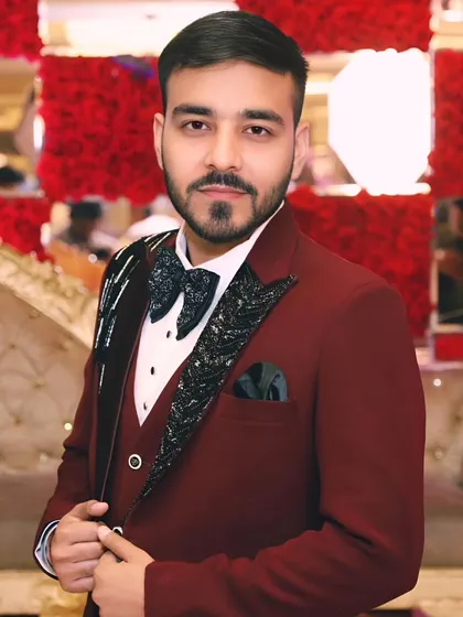 A sharp portrait of the groom-to-be looking dapper in a maroon tuxedo at his engagement ceremony.
