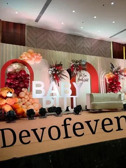 A wider view of the "Baby Puji" baby shower stage, showing the half-moon prop and the full arrangement of backdrops, marquee letters, and teddy bears.