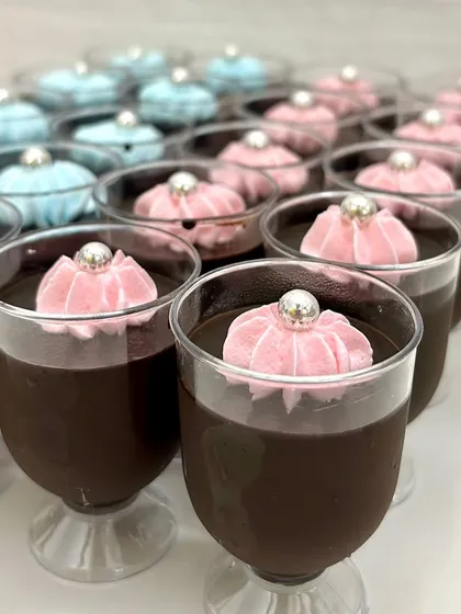 Individual chocolate mousse cups topped with pink and blue frosting and a silver pearl. These are a great no-mess dessert option for parties and dessert tables.