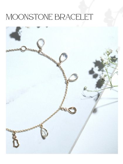 A dainty moonstone bracelet with teardrop-shaped gems and delicate gold charms. The ethereal glow of moonstone makes this piece truly special.
