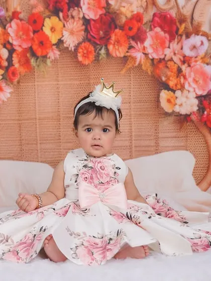 A vibrant floral-themed first birthday shoot. This little princess is surrounded by a stunning arch of colorful flowers, creating a fairytale-like portrait.