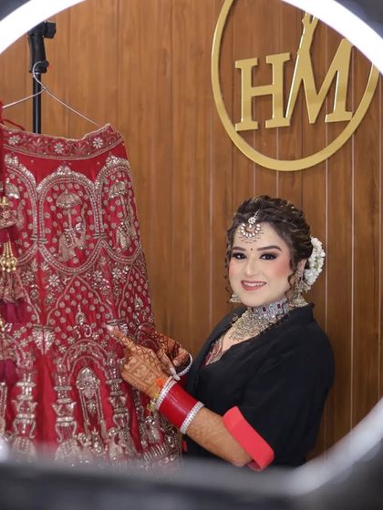 A classic getting-ready portrait. The bride points to the intricate details on her lehenga, a beautiful way to showcase the craftsmanship of her wedding outfit.