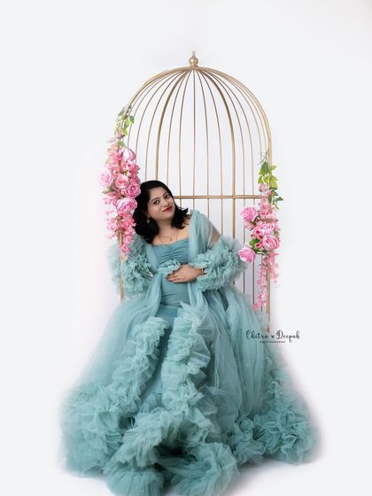 A whimsical and romantic setup featuring our popular golden birdcage prop. The soft blue ruffled gown and pink flowers complete this dreamy maternity portrait.