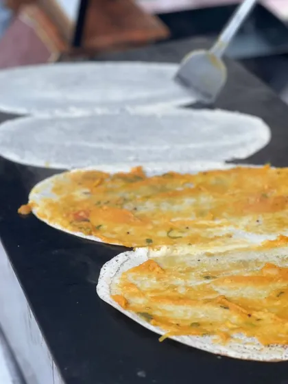A chef expertly preparing fresh dosas on a large griddle at one of our outdoor events. Live cooking adds a special touch to any celebration.