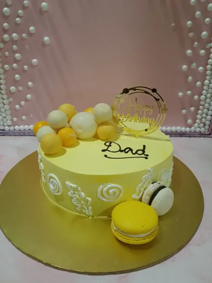 A bright and cheerful cake for Dad. The yellow theme is complemented by white chocolate spheres and delicate macarons.