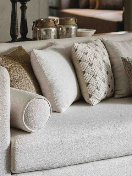 We love layering textures. Here, a variety of cushions in neutral tones with different weaves and patterns adds depth and comfort to a simple, elegant sofa.