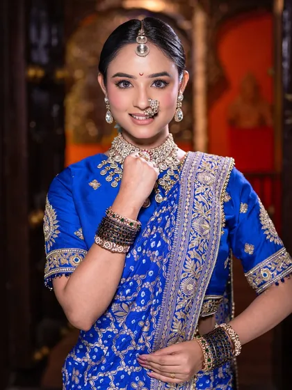 The quintessential Maharashtrian bride pose. Her makeup is kept clean and radiant, drawing attention to the beautiful traditional jewelry and her bright, happy expression.