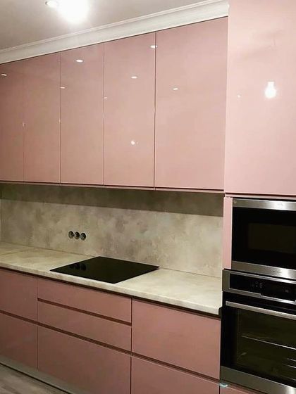 A sleek and modern kitchen with glossy, dusty-rose colored cabinets. The handle-less design and integrated appliances create a seamless look, perfect for a contemporary home.
