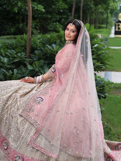 A beautiful bride seated in her pastel pink and ivory lehenga. The soft pink dupatta adds a touch of romance to the overall look.