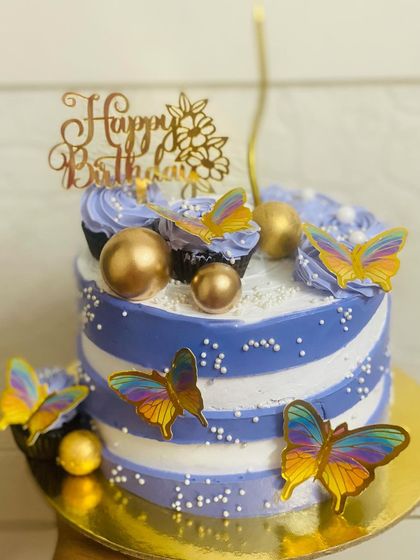 A beautiful blue and white striped cake adorned with colorful butterflies.