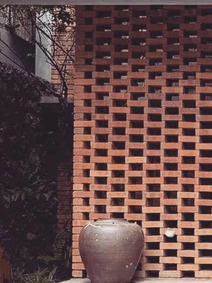 A brick jali screen provides privacy while allowing for the natural flow of light and air. This simple, contemporary feature adds texture and a traditional touch to the building's modern architectural design.