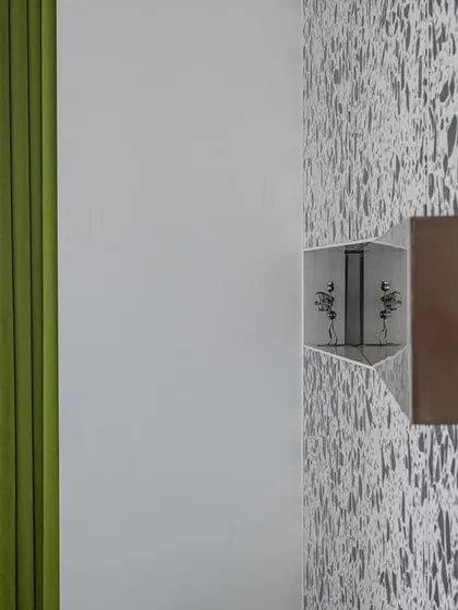 A detail from the 'Wedged Haus' guest room, where a reflective copper cuboid is wedged into the terrazzo headboard paneling. This small intervention becomes an object of focus, demonstrating our interest in using pure geometric forms and material contrast to create visual impact.