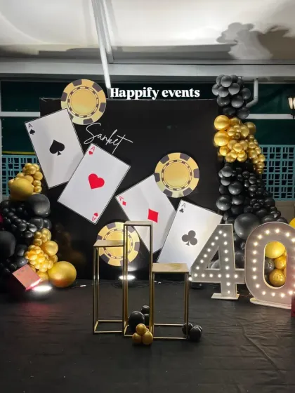 A high-stakes Casino Night theme for a 40th birthday. The backdrop features oversized playing cards, casino chips, and a light-up marquee number.