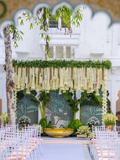 I love creating timeless looks, like this South Indian ceremony setup. The stage features a canopy of hanging jasmine and tuberose, traditional banana plantains, and a beautiful hand-painted backdrop, all coming together for an authentic and elegant wedding atmosphere.