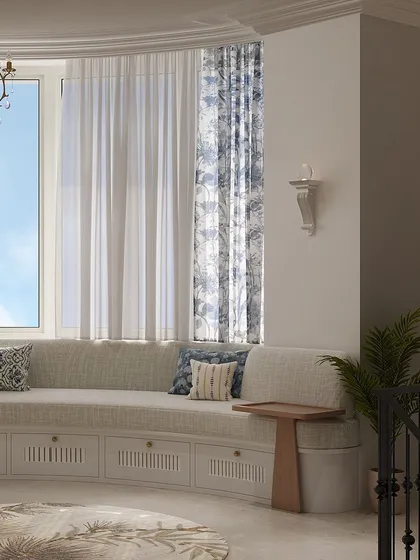 The curved window seat is a highlight of the room, offering ample seating and hidden storage below. The patterned blue curtains add a final decorative touch.