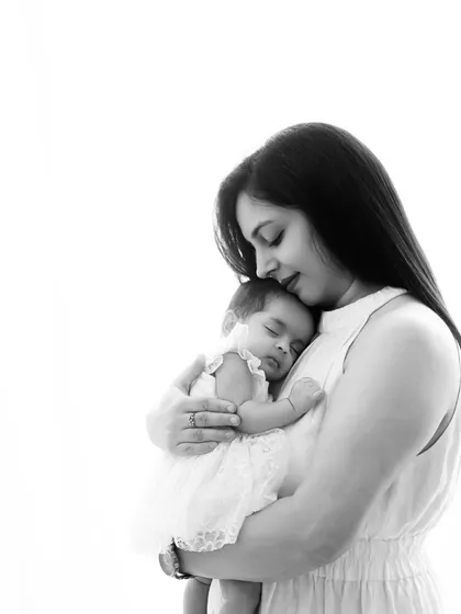 A mother cradles her sleeping newborn against her chest. This high-contrast black and white image beautifully captures the peace and security a baby feels in her mother's arms.