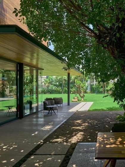 The deep, shaded patio of the house provides a comfortable outdoor living area, perfectly integrated with the lawn and the existing tree.