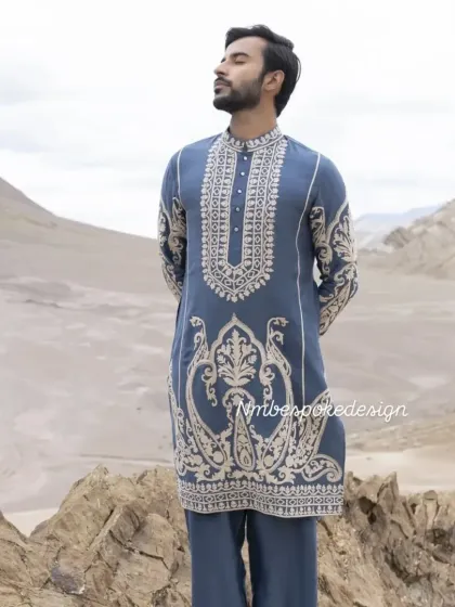 A dusty blue kurta with intricate white paisley and floral embroidery. The outdoor setting highlights the beautiful craftsmanship.