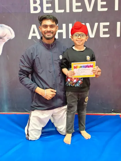 This young gymnast in his turban proudly holds his certificate, a great moment of achievement.