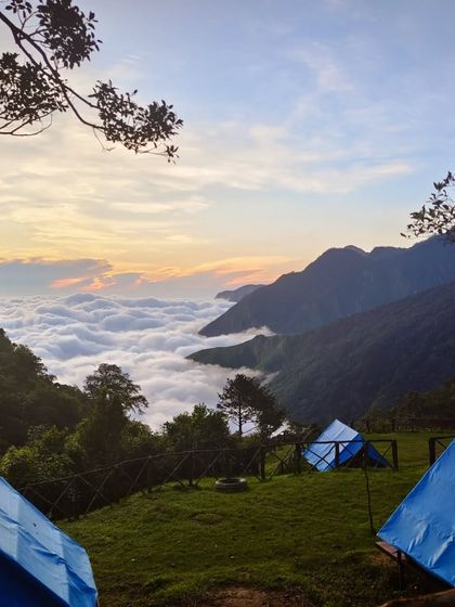 A beautiful shot of the campsite at dawn or dusk, overlooking the cloud-filled valley.