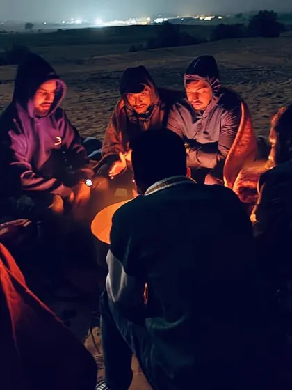 A candid moment of our group sharing stories and warmth around a bonfire in the desert. This is where strangers become friends.