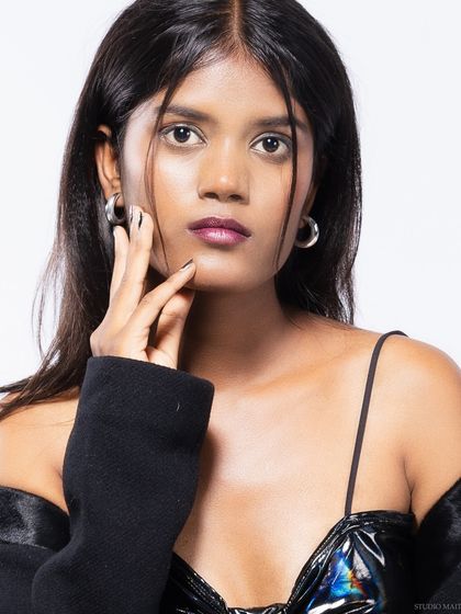 A close-up portrait of a model, focusing on her direct gaze and edgy styling.