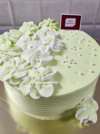 A simple and elegant anniversary cake with a pistachio green frosting and delicate white buttercream flowers.