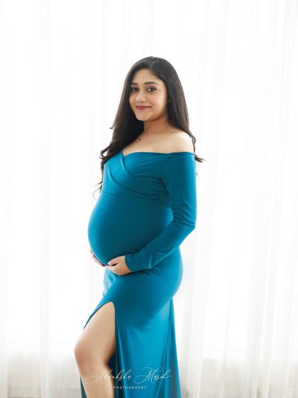 Simple, elegant, and glowing. This off-shoulder teal gown with a side slit is a classic choice that beautifully accentuates the baby bump for a timeless and flattering portrait.